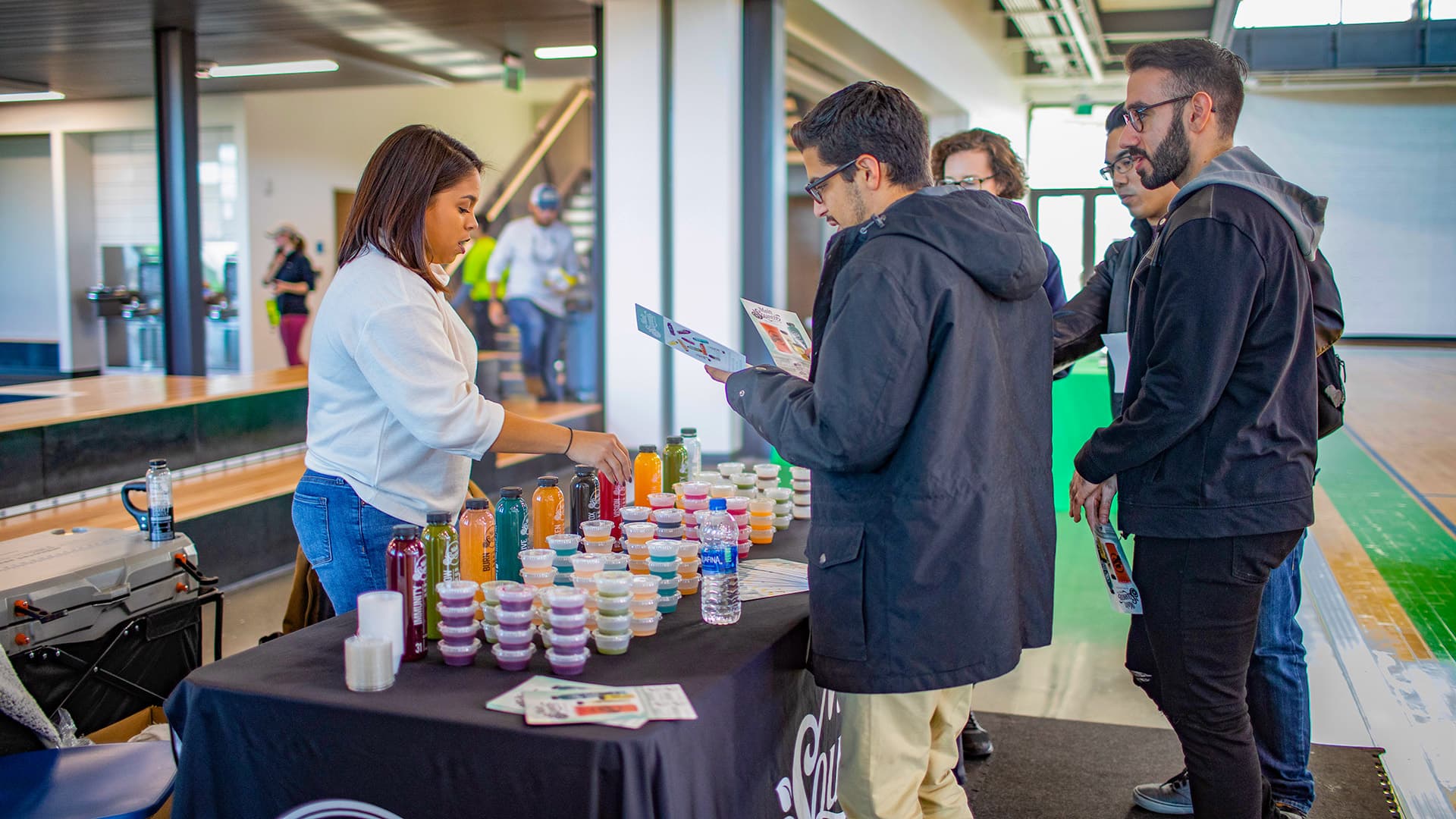 Students trying juice samples at a vendor table in the Recreation and Wellness Center