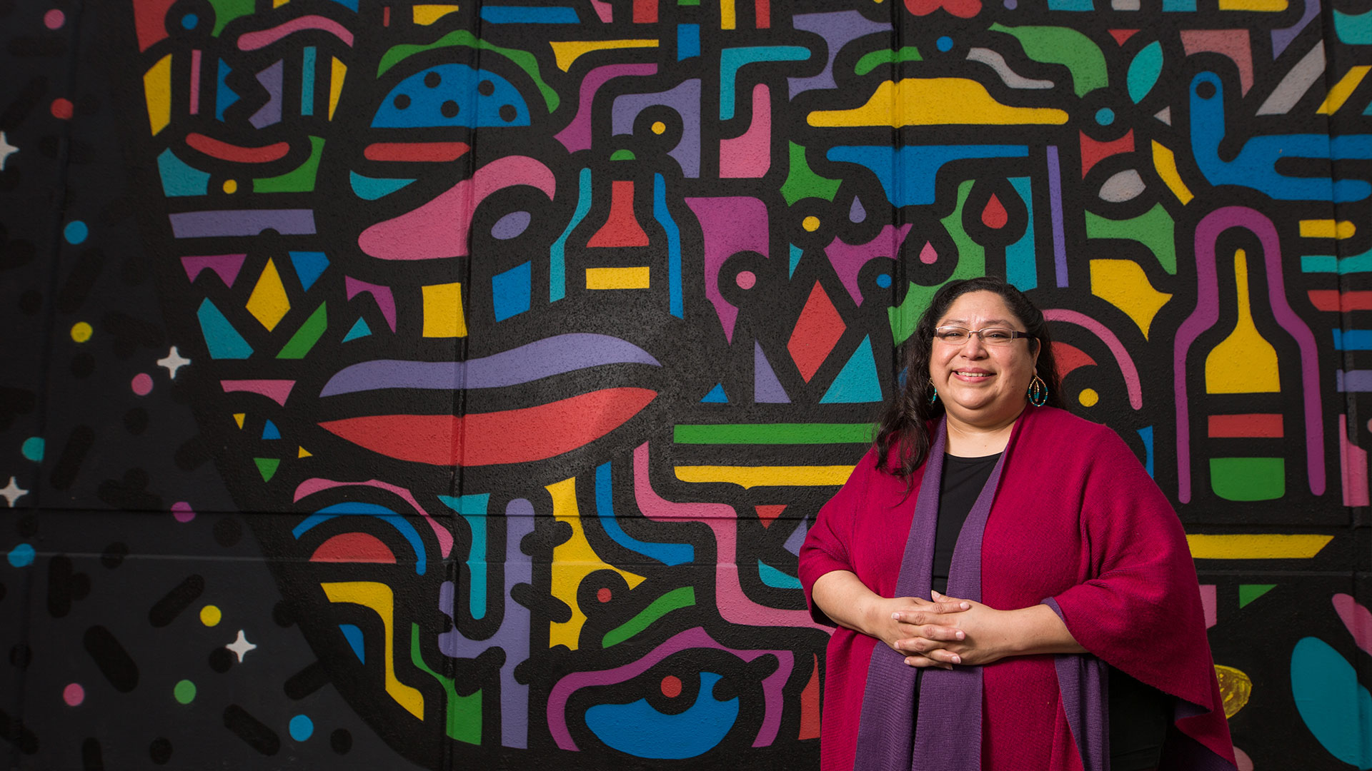 A faculty member in front of a painted mural