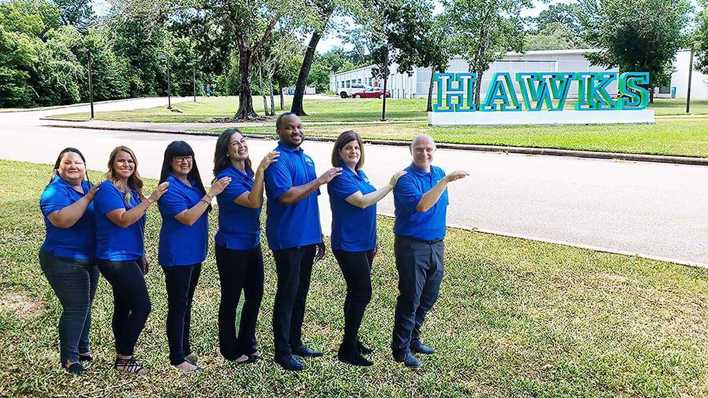 Team photo standing outside on campus by the UHCL Letters