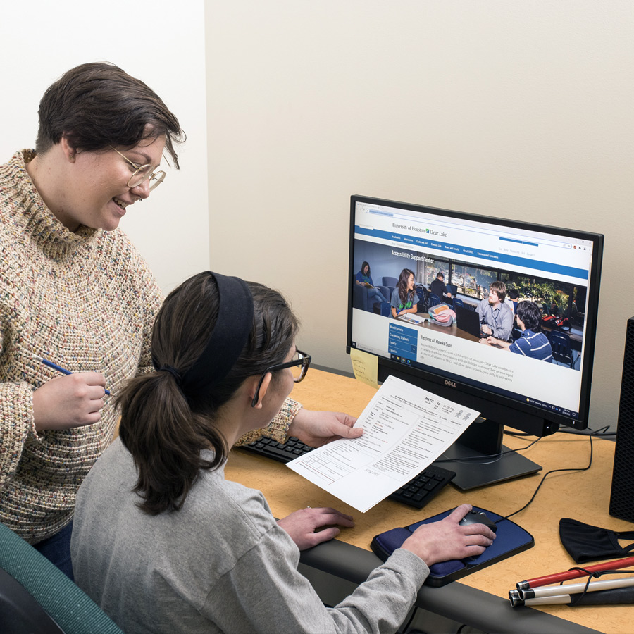 Photo of Accessibility Support Center staff assisting UHCL student sitting a computer