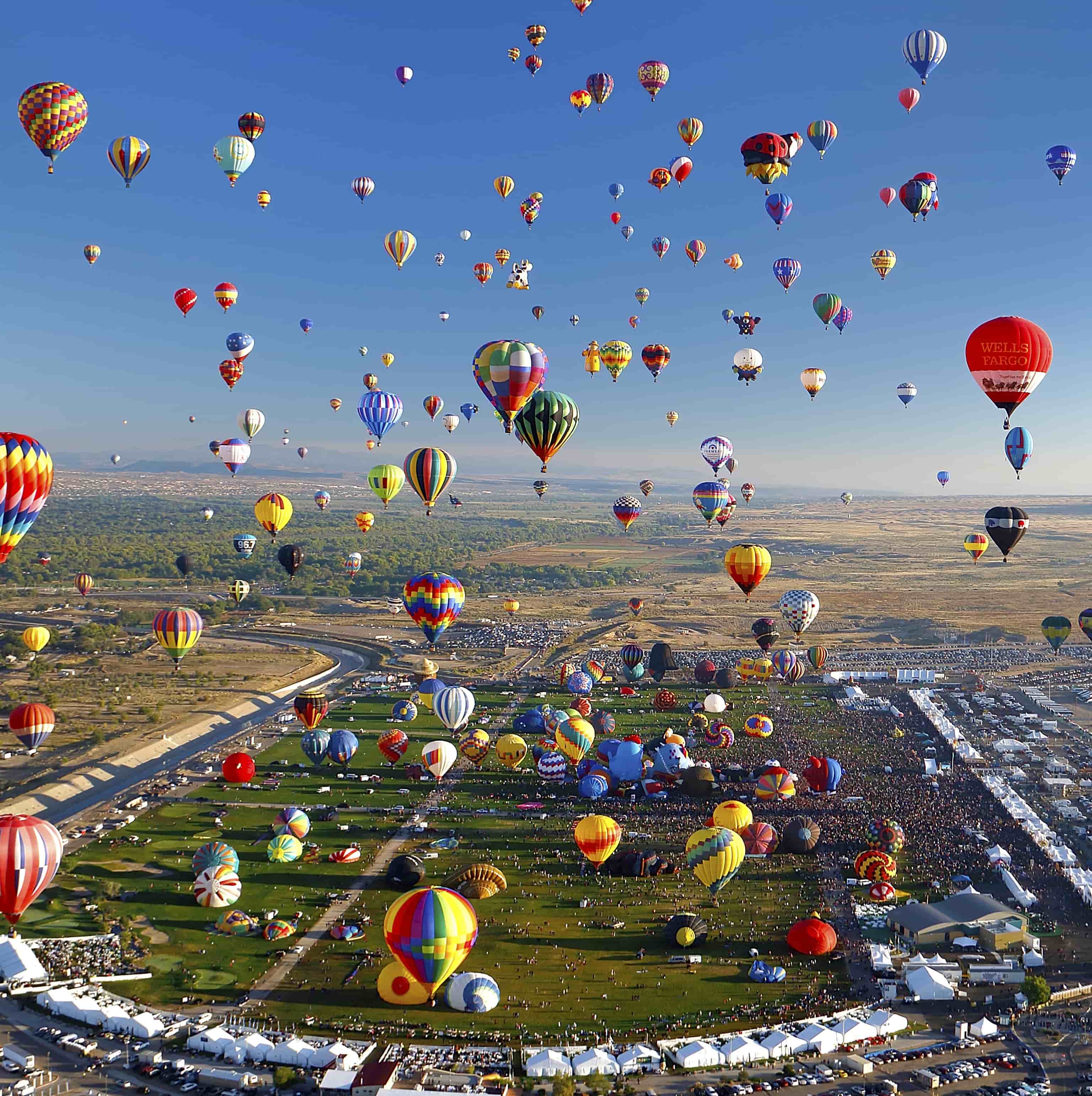 hundreds of hot air balloons rise from a large field located in alberquerque new mexico