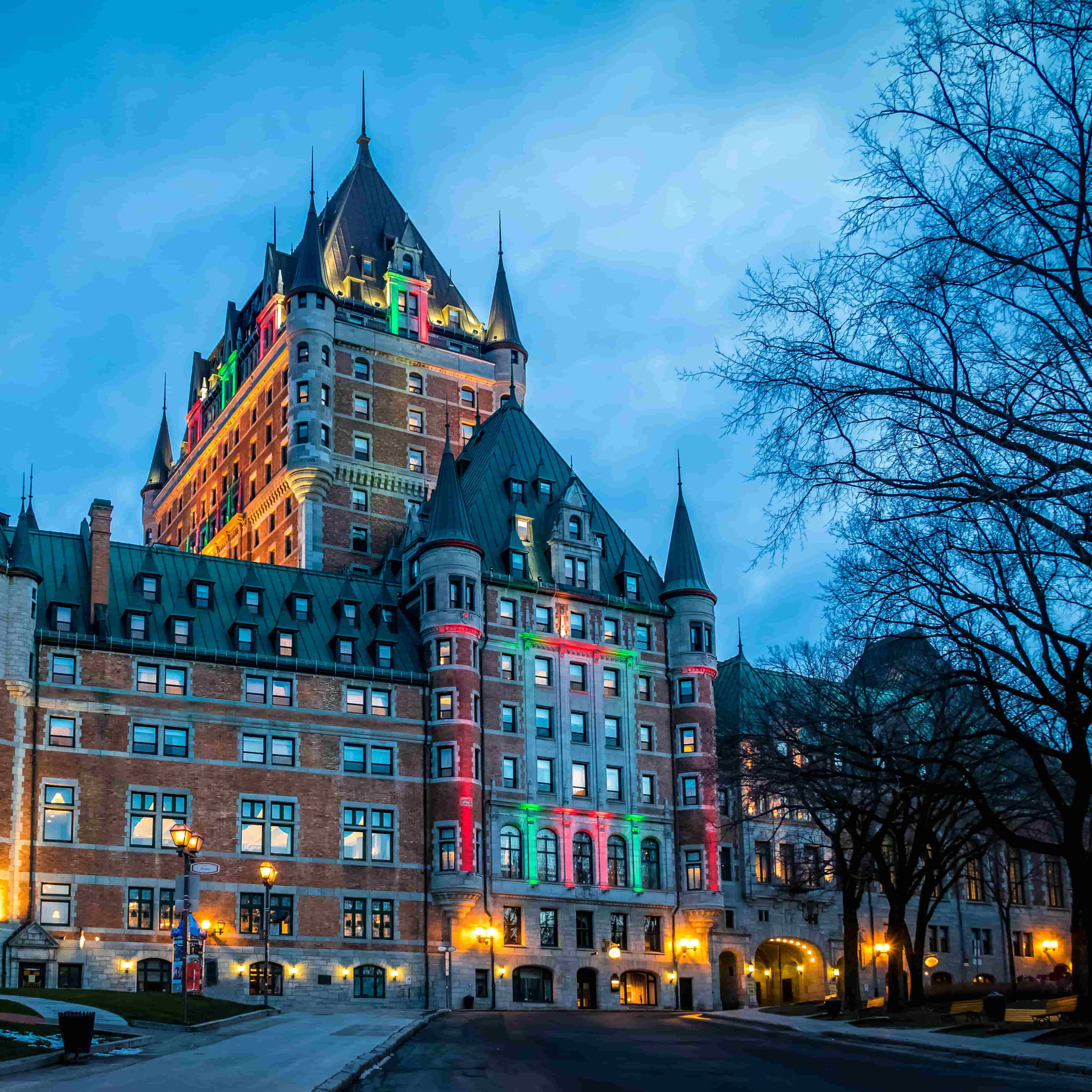 frontenac castle in montreal stands lit up in red and green lighting for christmas