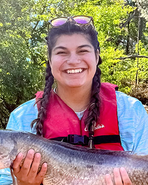 Lauren is on a boat and holding a fish.