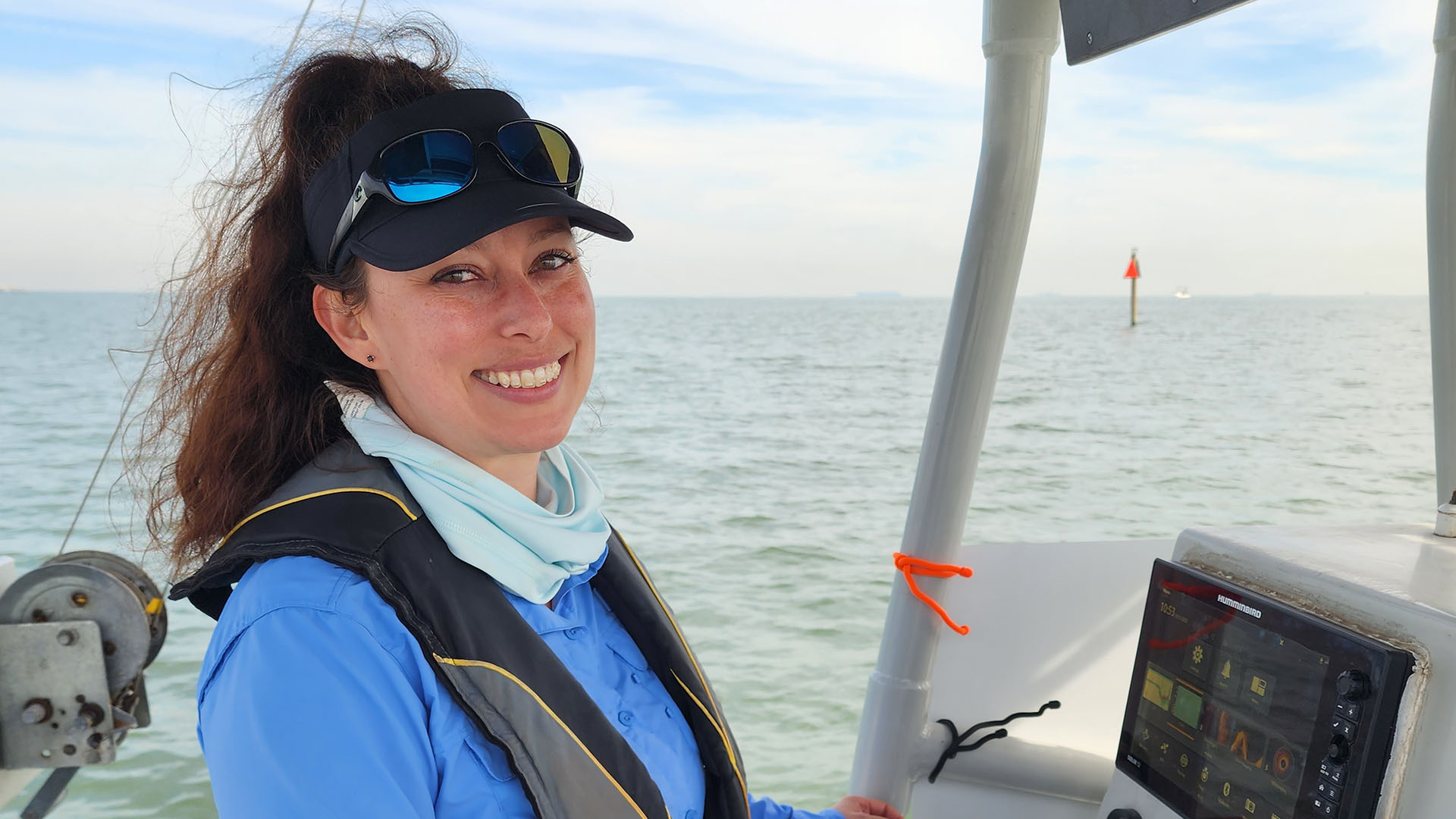 Sherah, smiling at the camera, is on a boat with the ocean horizon in the background.