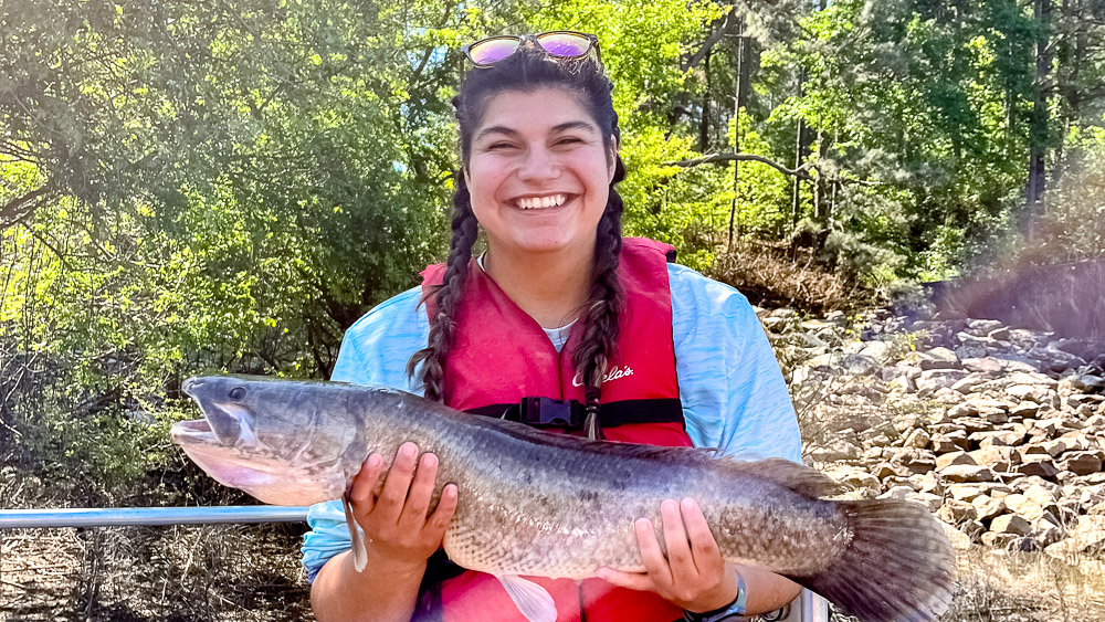 Lauren is holding a large fish and smiling at the camera.