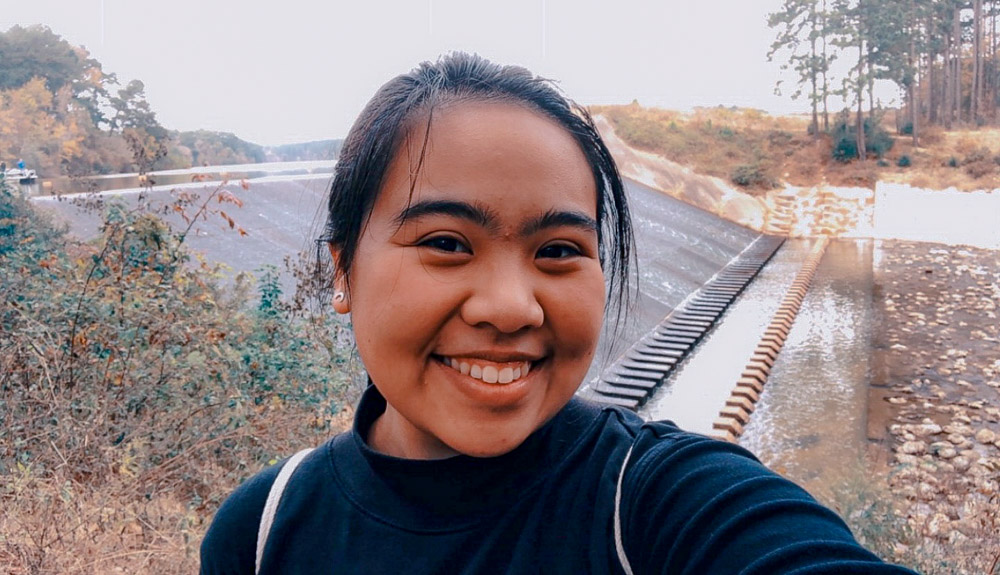 Princess is standing in front of a spillway and smilling at the camera.