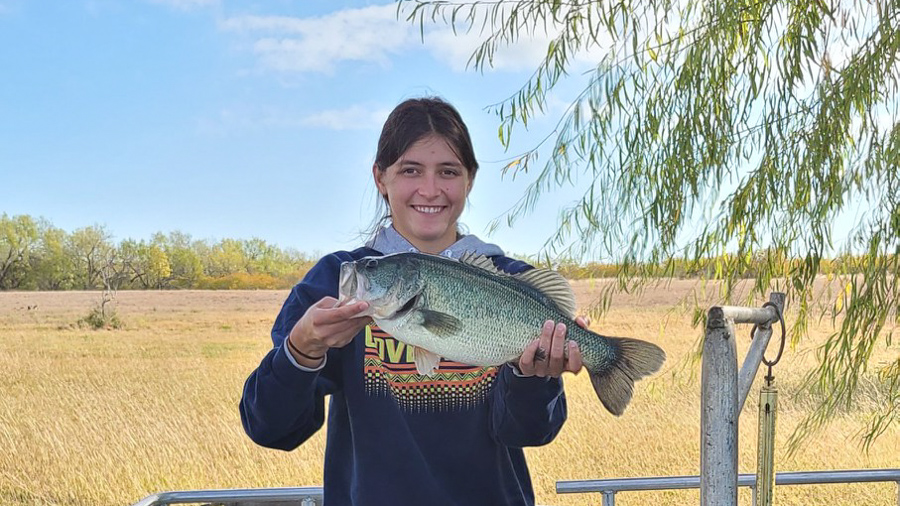 Tenley is holding up a large fish and smiling at the camera.