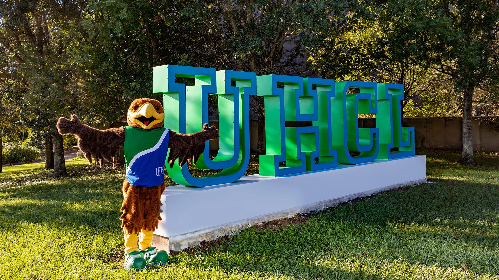 Hunter Hawk standing in front of the UHCL letters