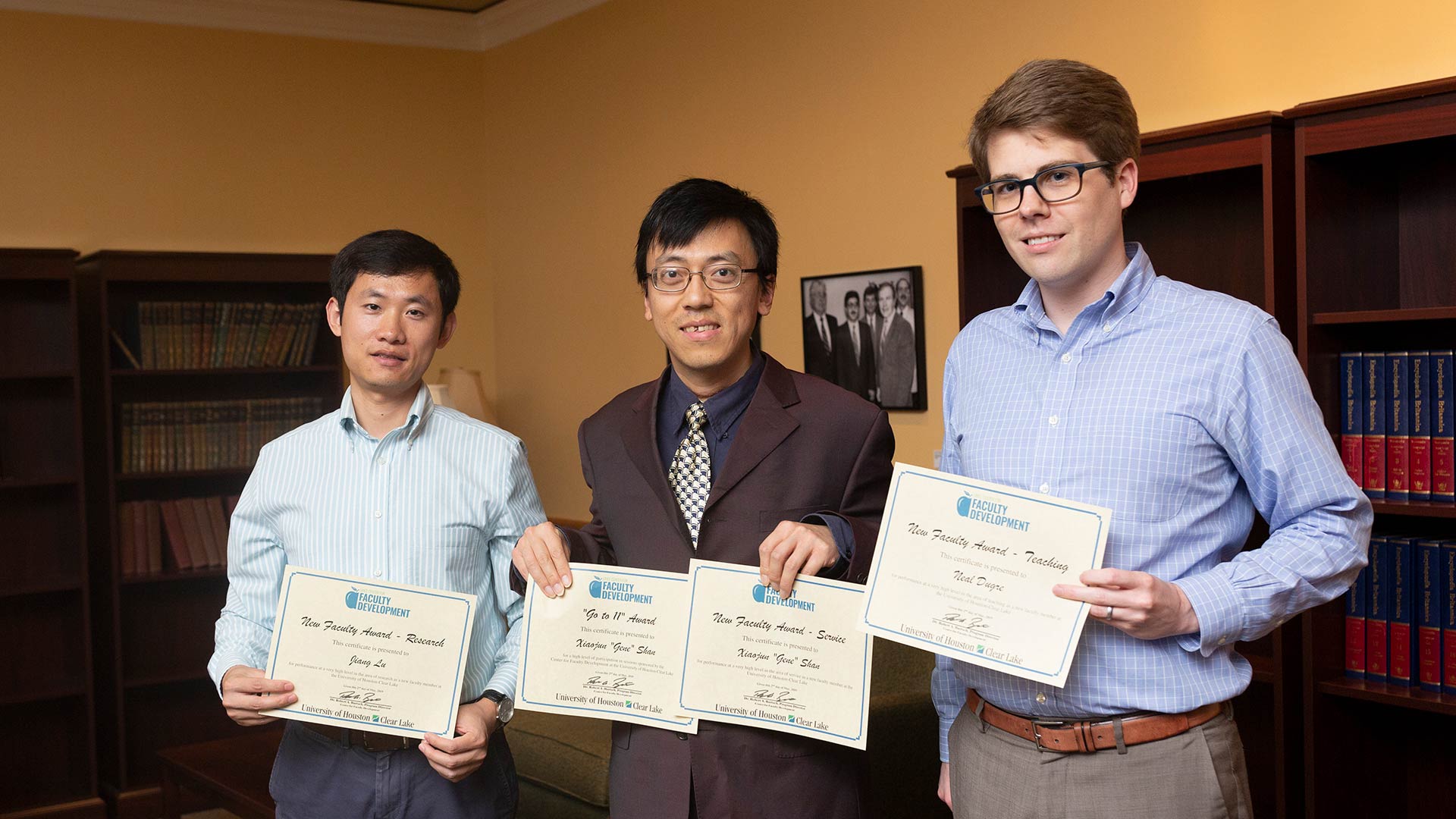 Three faculty members holding certificates