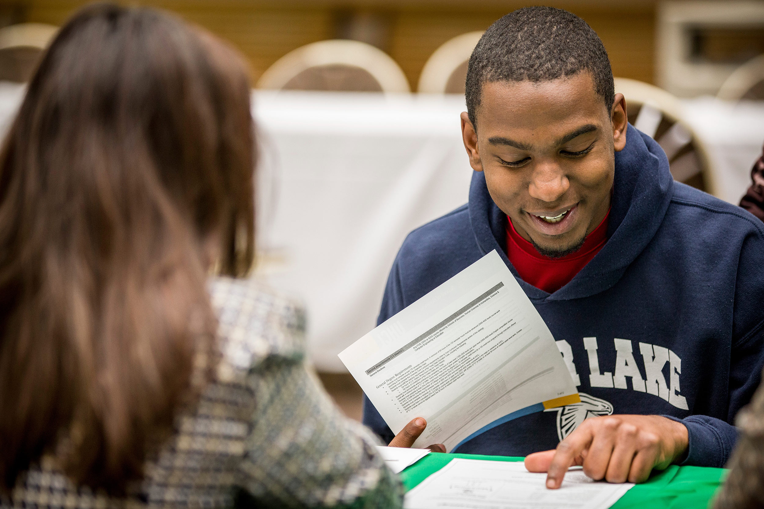 Student smiling and reading through papers