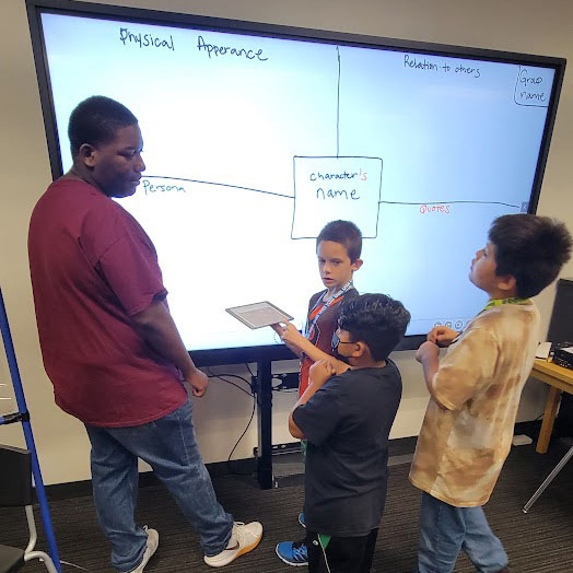 Photo of Zachary Sheriff working with young students at a digital board