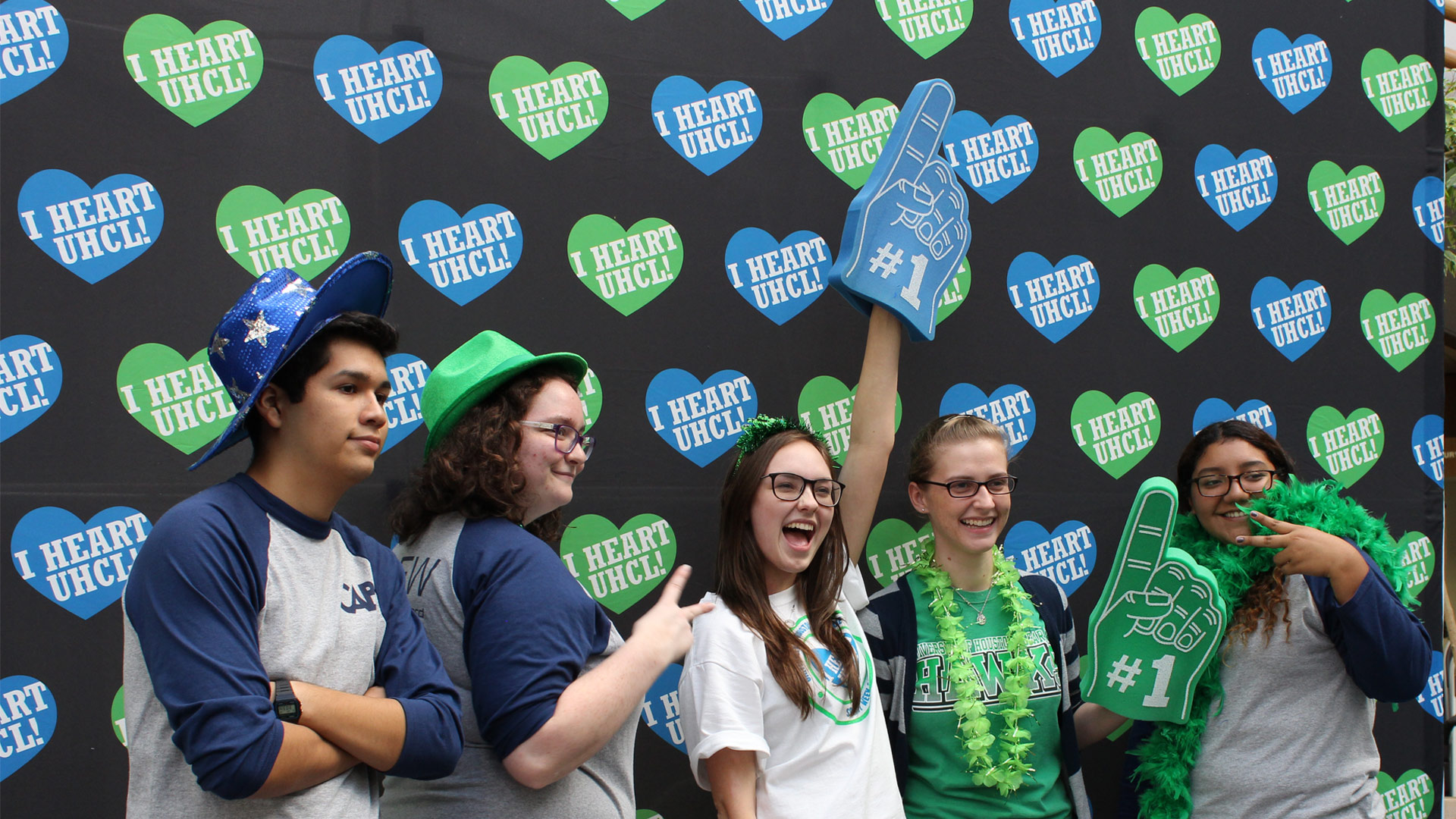 Students with blue and green foam hands and boas at I Heart UHCL