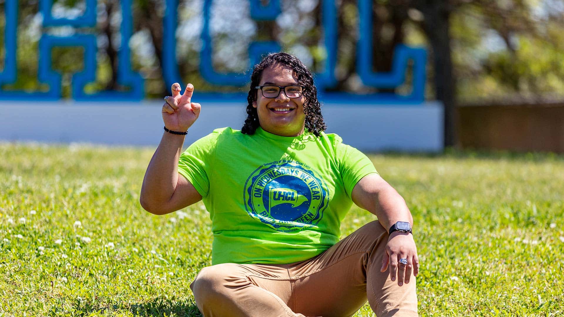 A student with the UHCL letters, hand raise in "The Claw"